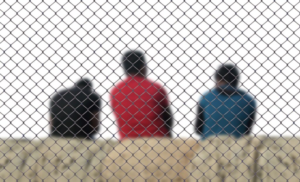 Menschen hinter einem engmaschigen Gitter